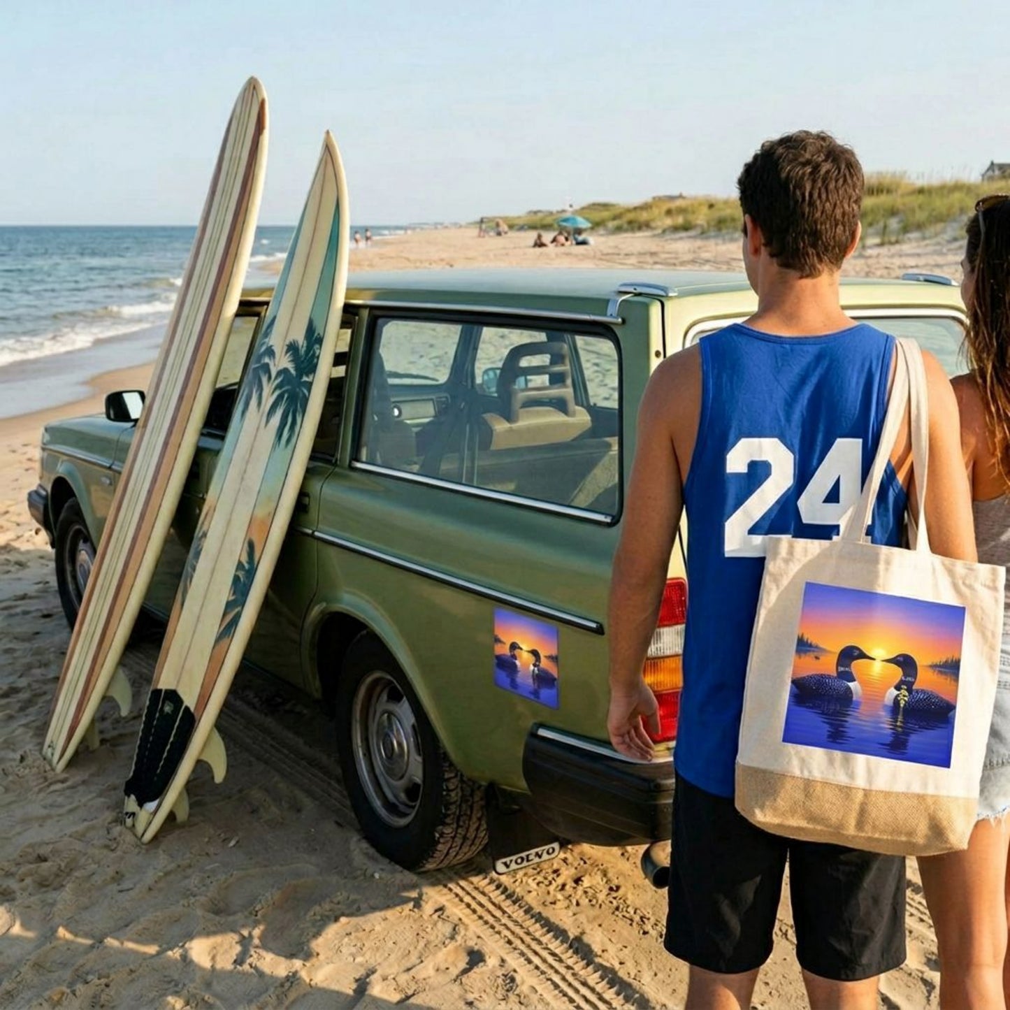 Two people at the beach, looking at a car with surfboards leaning on it and it has a sunrise loon car magnet on the side of the car. Person has a tote bag that matches the design of the magnet.