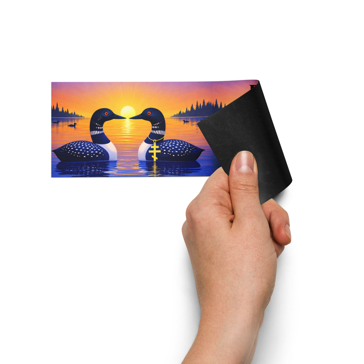Showing the magnetic backing of a colorful 10 by 3 car bumper magnet showing two loons on a sunset lake with golden reflections, evergreen trees, and the words “Reheat as Often as Needed.”
