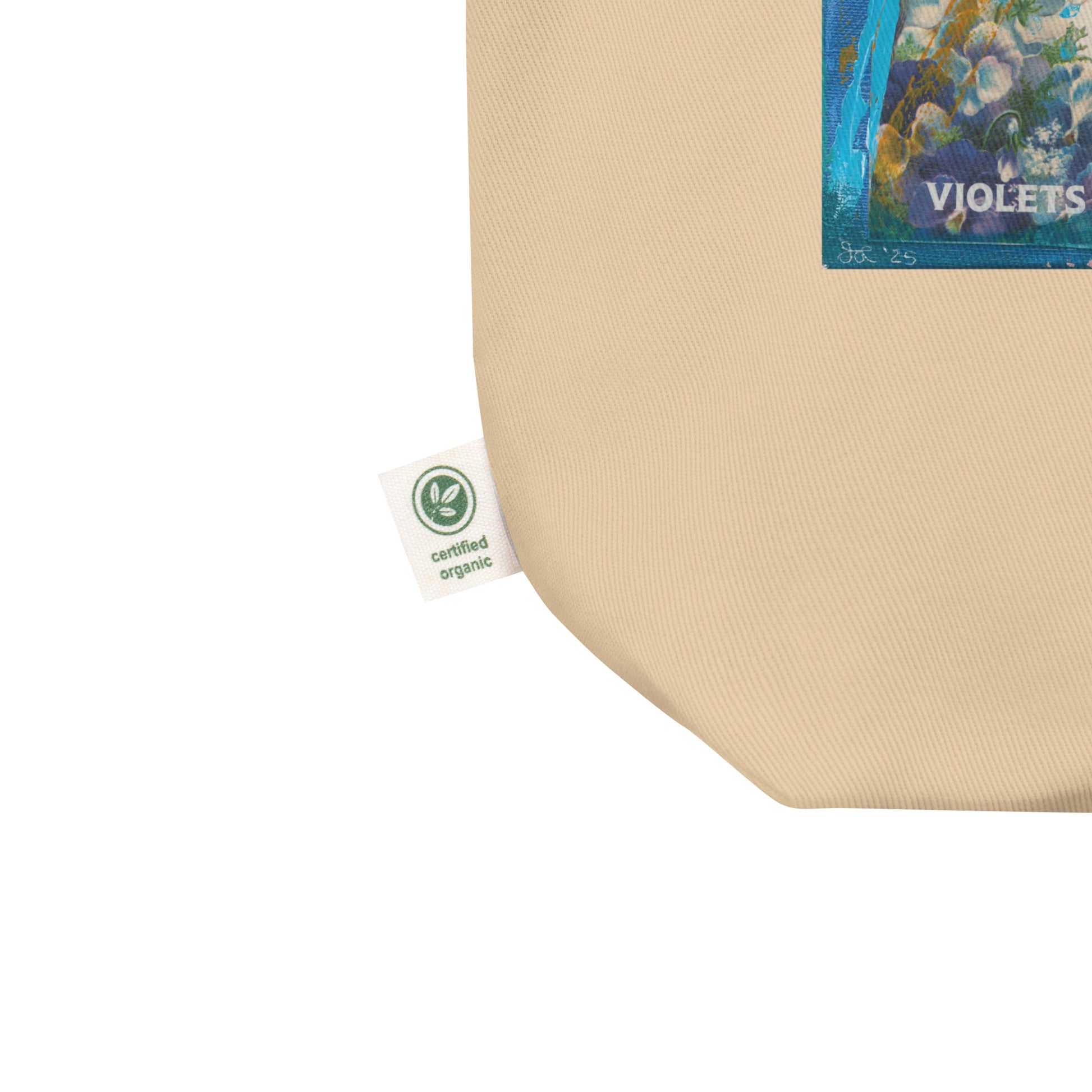 Image shows the corner of the purple floral eco tote bag hello there sweet bloom, showing the tag which says certified organic.
