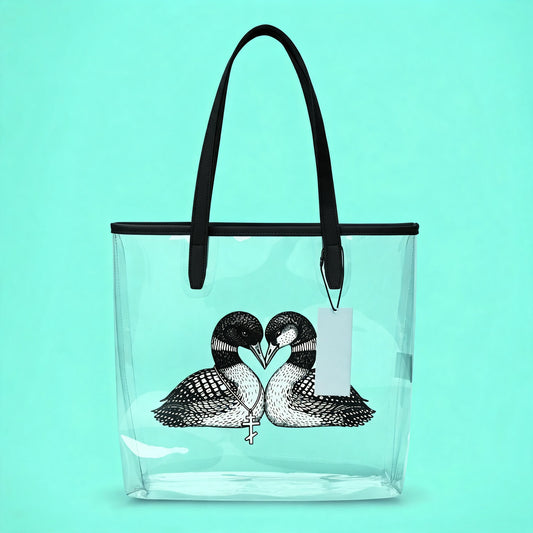 black and white loons heart tpu clear tote bag placed in front of a light aqua background. Clear bag has a image of two loons with beaks together forming a heart.