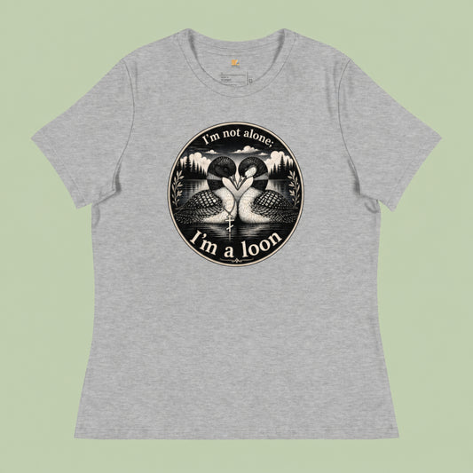 Heather gray women’s graphic tee featuring two loons facing one another on a moonlit lake, their necks forming a heart, with the message “I’m not alone; I’m a loon.”