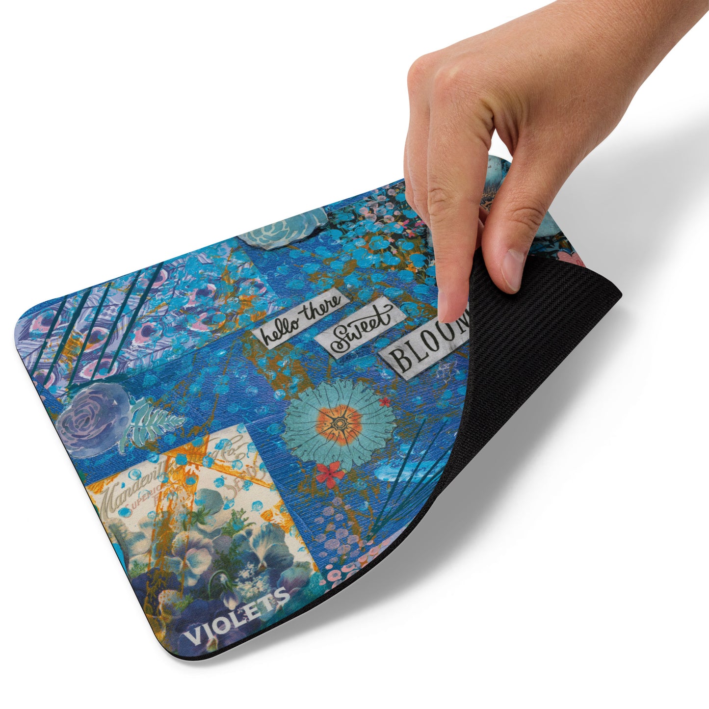 An image of the Hello There Sweet Bloom purple floral mouse pad with the edge lifted up to show the natural rubber grip on the bottom.