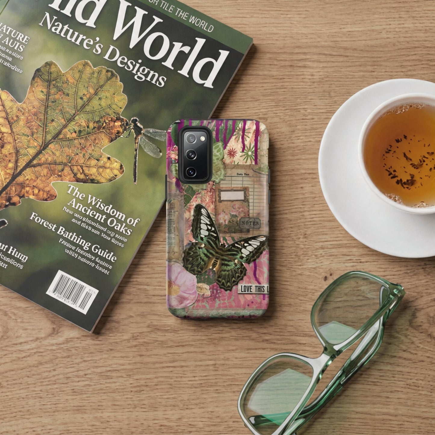 a pink floral butterfly Samsung case love this life quote on a wooden table with a cup of tea, magazine and green eyeglasses.