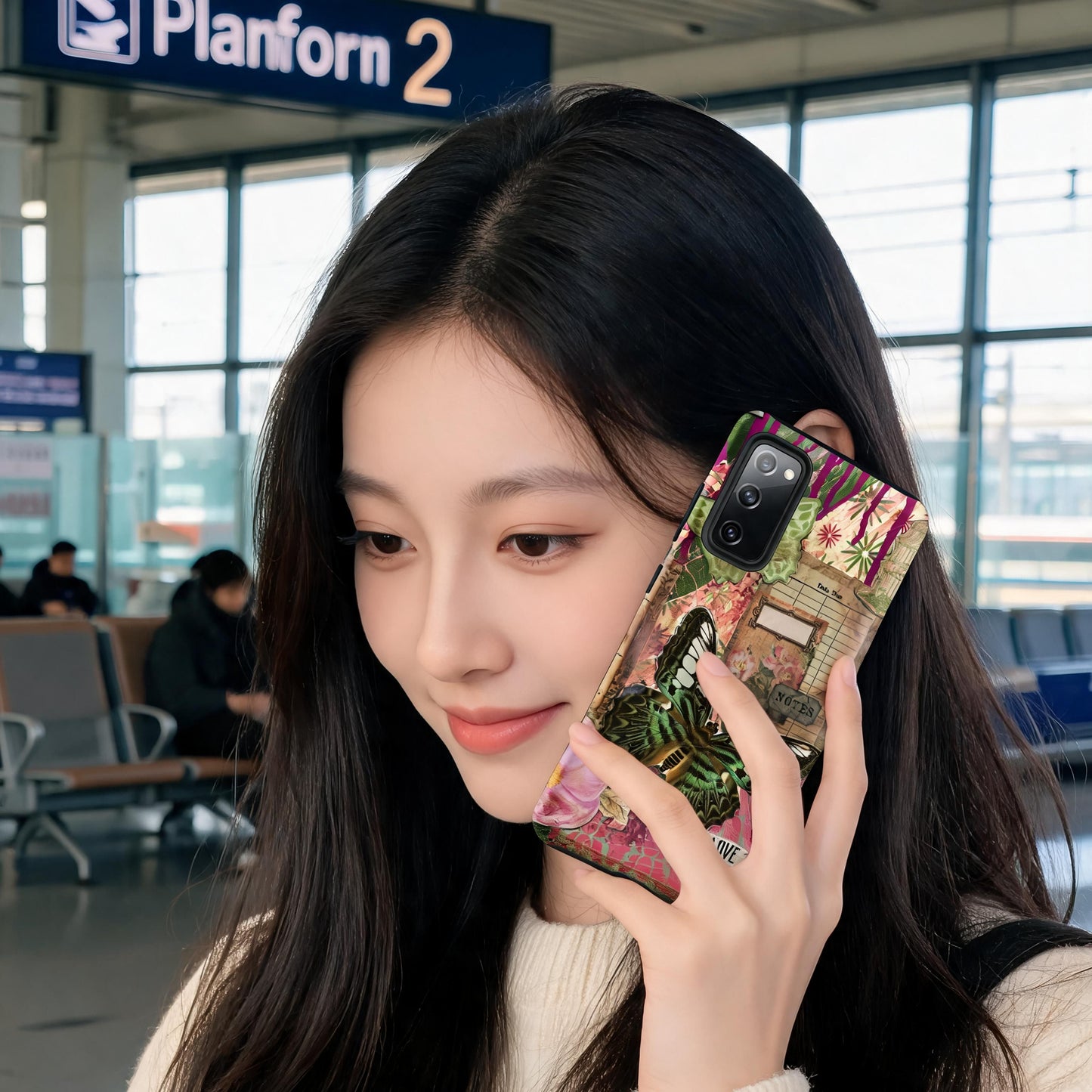 a woman on the phone at a train station. She has a pink floral butterfly Samsung case love this life quote.