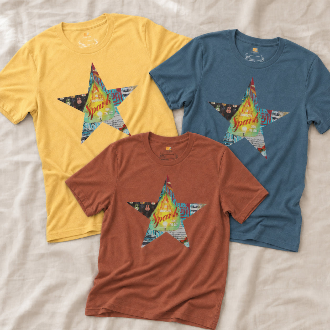Three Star tee shirts with a colorful mixed-media star design and the words spark of inspiration on a soft unisex t shirt.

