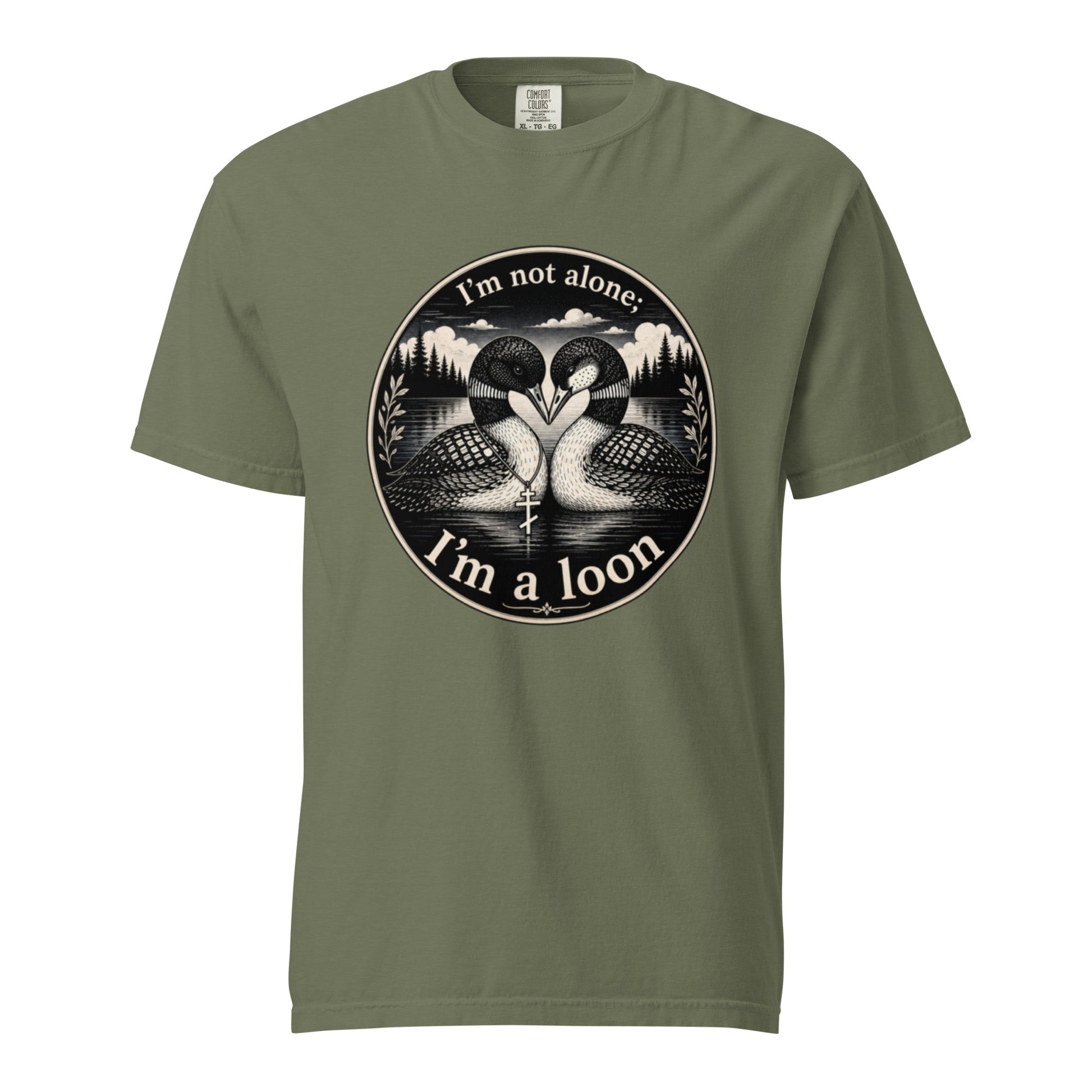 A Moss colored short-sleeve crewneck t-shirt featuring a circular black and white graphic of two loons facing each other in front of a lake and mountains, with the text 'I'm not alone. I'm a loon'.